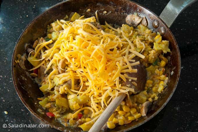 Folding in shredded cheese and leftover cornbread