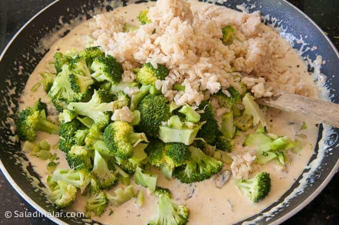 Adding broccoli and rice to cheese and cream sauce
