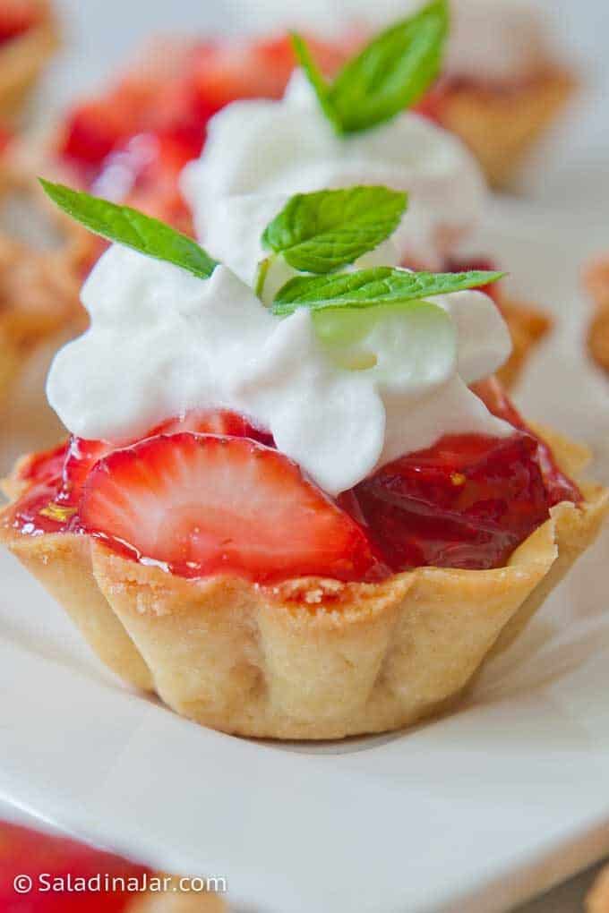 up-close shot of mini strawberry tart with whipped cream