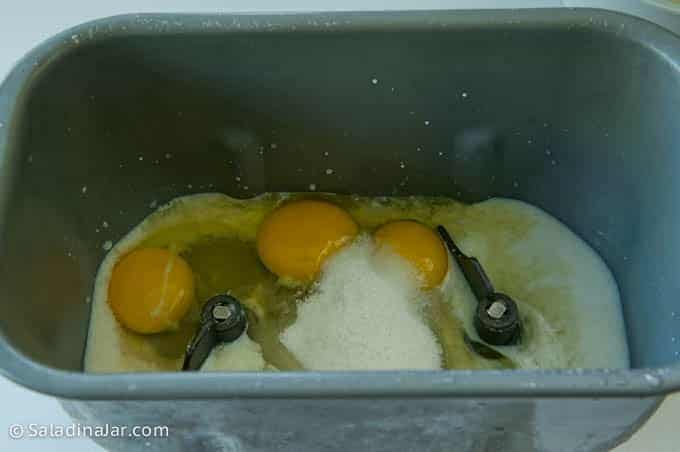 adding eggs, sugar and salt to bread machine pan