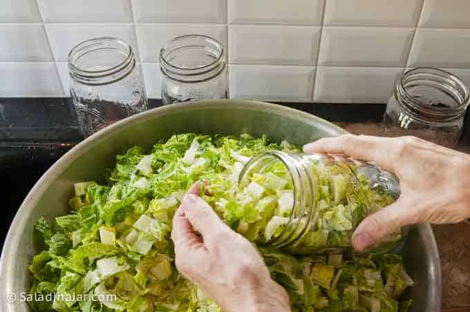 stuffing Mason jars with lettuce by hand