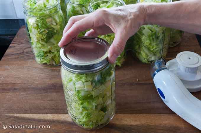 putting collar on top of sealed jars of salad