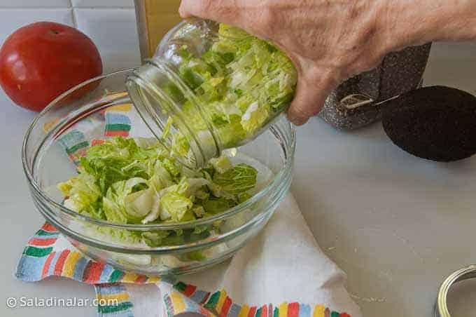 pouring a vacuum-sealed romaine lettuce salad into a bowl to eat