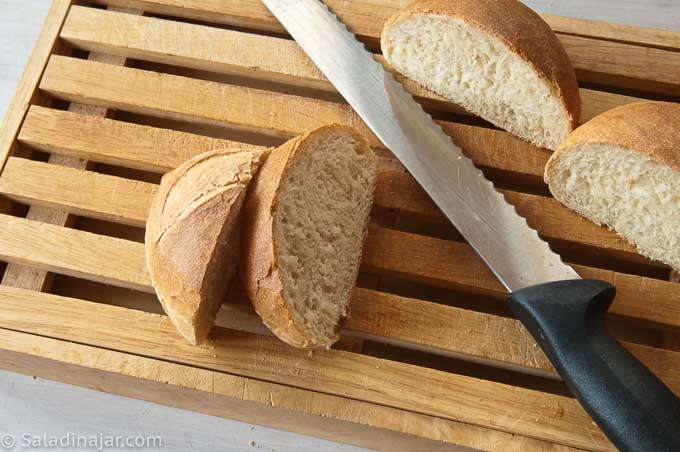 cutting really crusty rolls on a slatted cutting board