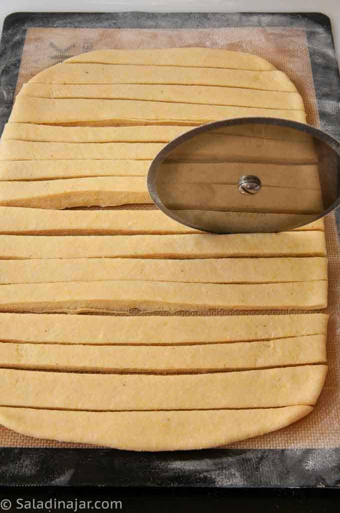 Cutting the dough into strips with a pizza cutter.