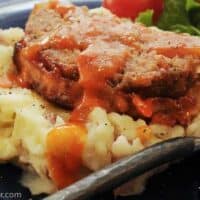 blackened meatloaf on top of mashed potatoes and drizzled with tomato gravy.