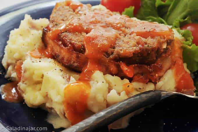 blackened meat loaf on top of mashed potatoes with tomato gravy