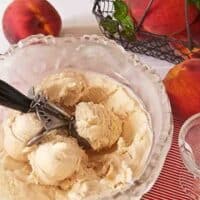 homemade peach frozen yogurt in a bowl with ice cream scoop