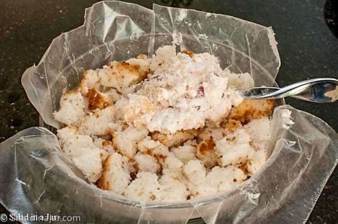 torn angel food cake pieces in a bowl lined with wax paper