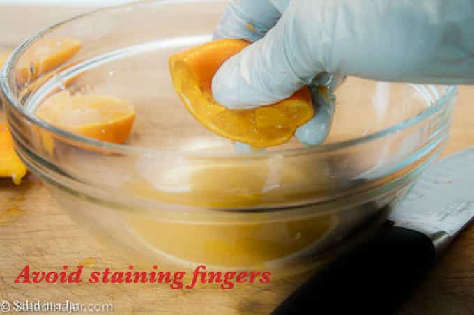 gloved hands squeezing oranges