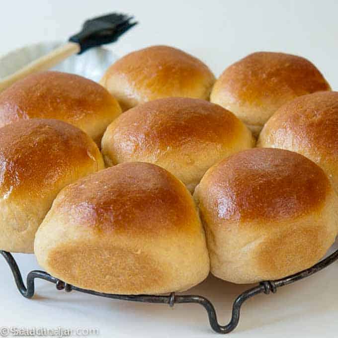 White whole wheat dinner rolls with a pastry brush on the side for butter.