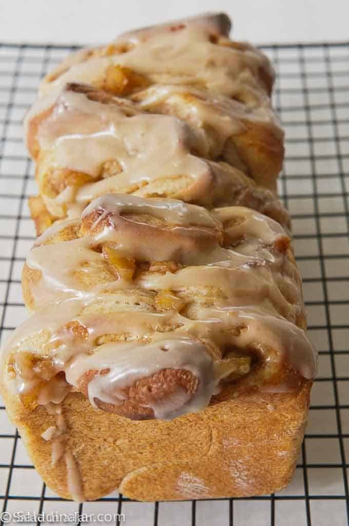 Apple Cinnamon Yeast Bread with frosting on top sitting on a cooling rack
