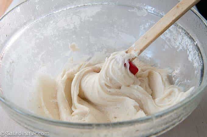 beating frosting with a spatula.