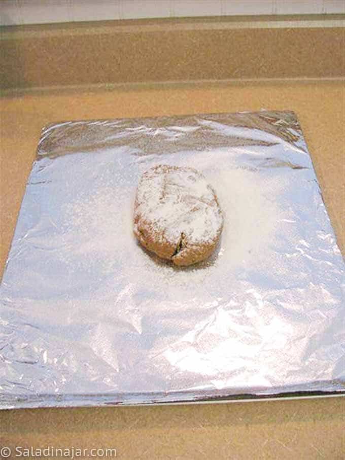 rolling out gingerbread dough on foil-lined cookie sheet