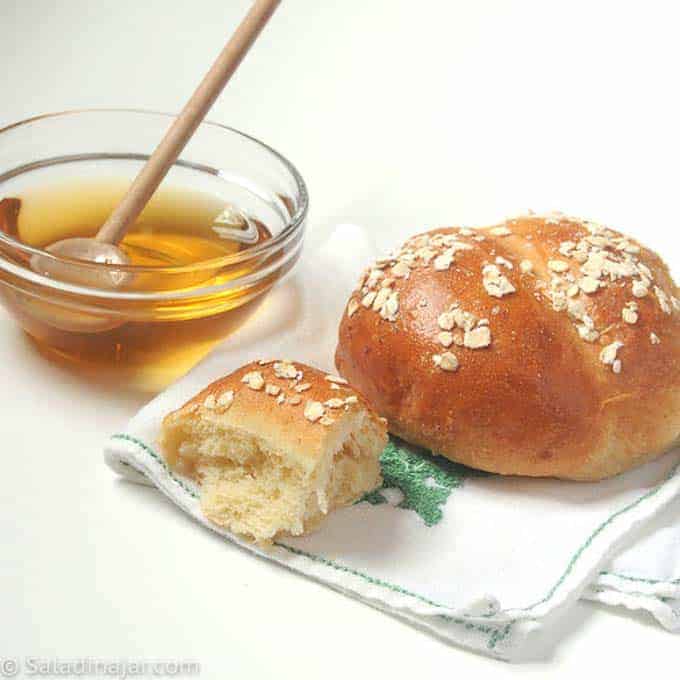 oatmeal roll sitting next to a bowl of honey.