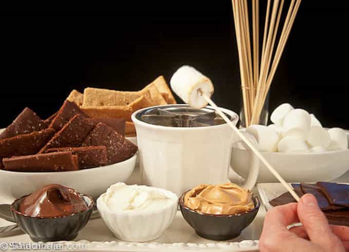 grilling a marshmallow over a homemade sterno grill on the s'more charcuterie tray