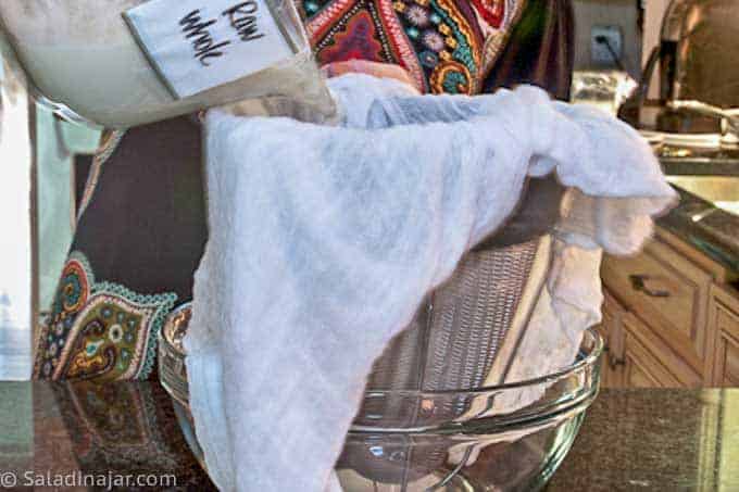 straining raw whole milk to make Greek yogurt