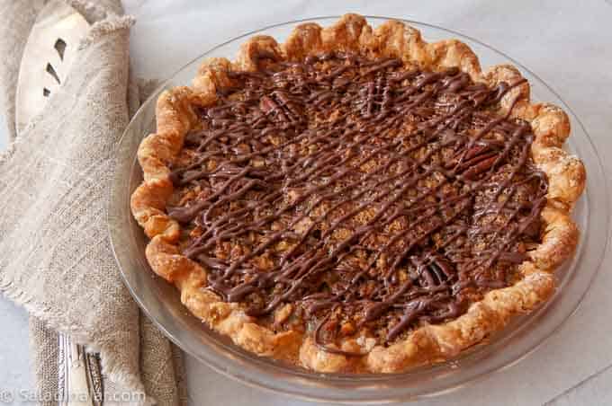 Uncut baked pecan pie with chocolate drizzle