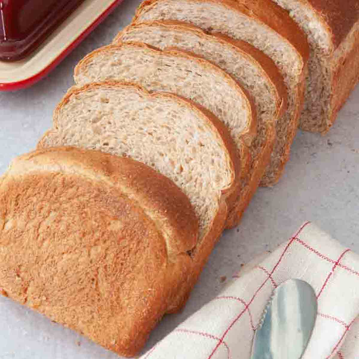 sliced honey wheat bread with a butter dish in the background