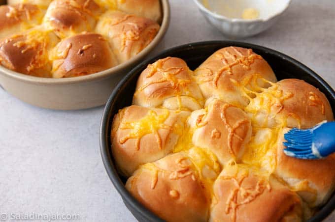 Baked Cheese Dinner Rolls in a pan. brushed with butter.