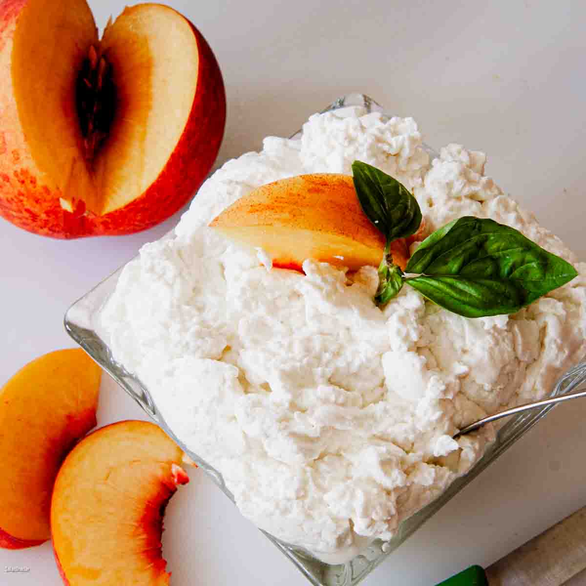 a bowl of ricotta made with yogurt whey surrounded by fresh peaches.