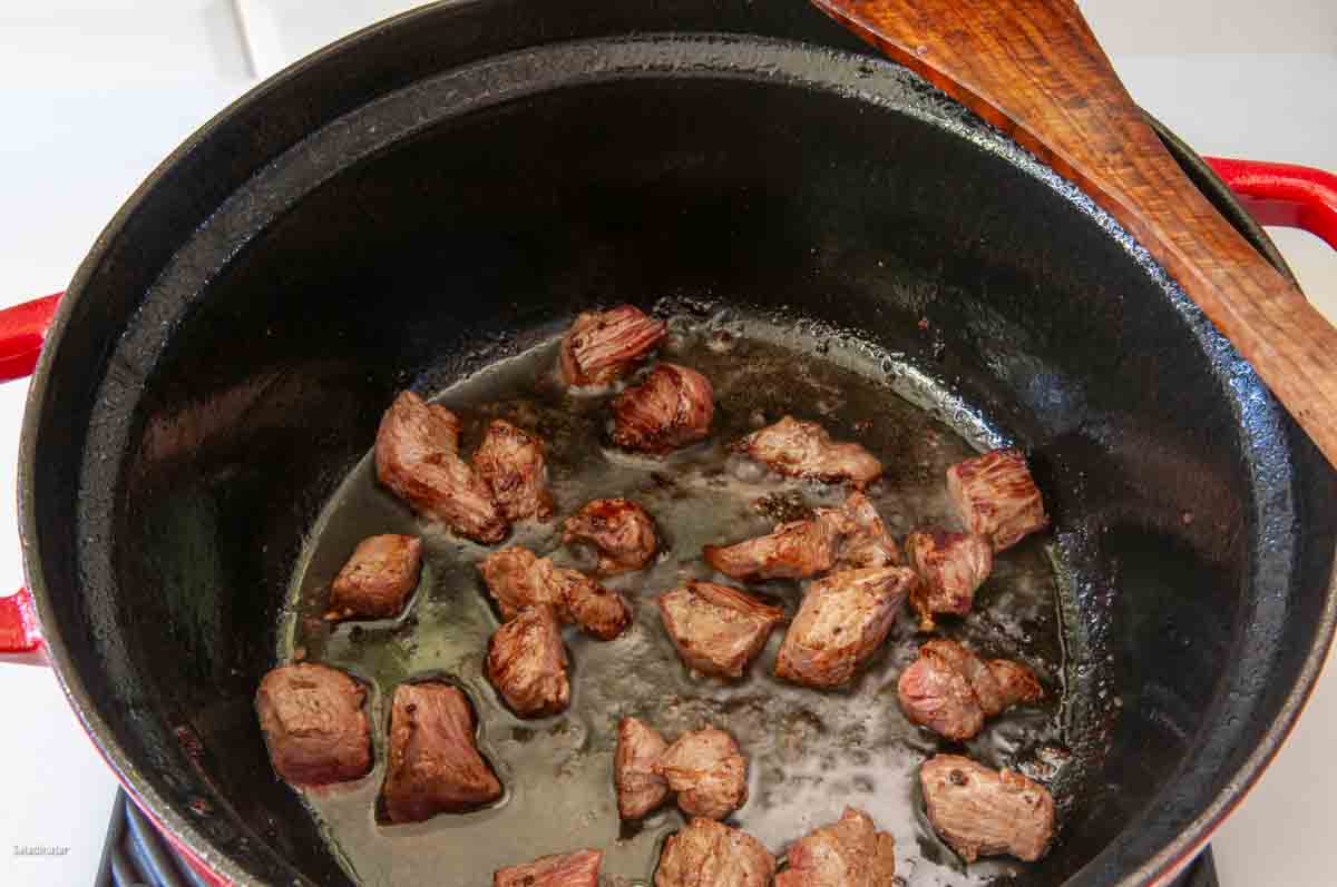 Browning beef cubes in a Dutch oven.