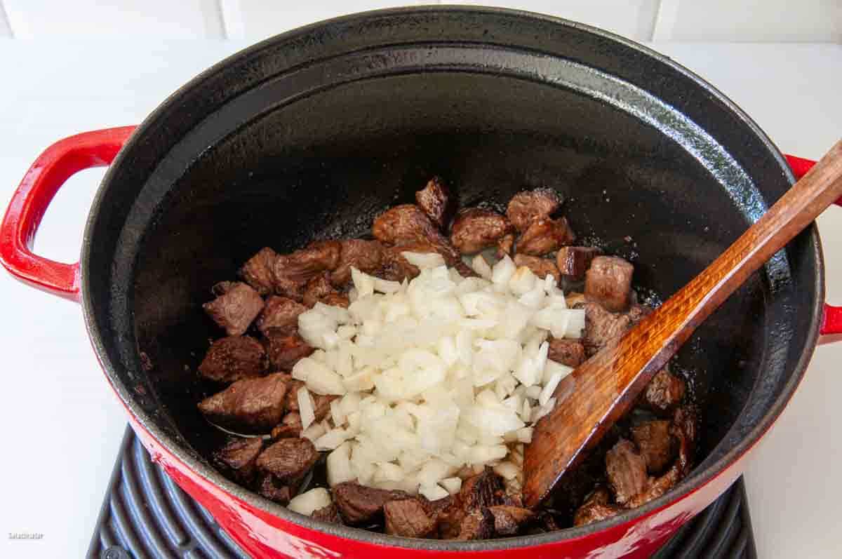 Cooking onions with the beef chuck until they soften.