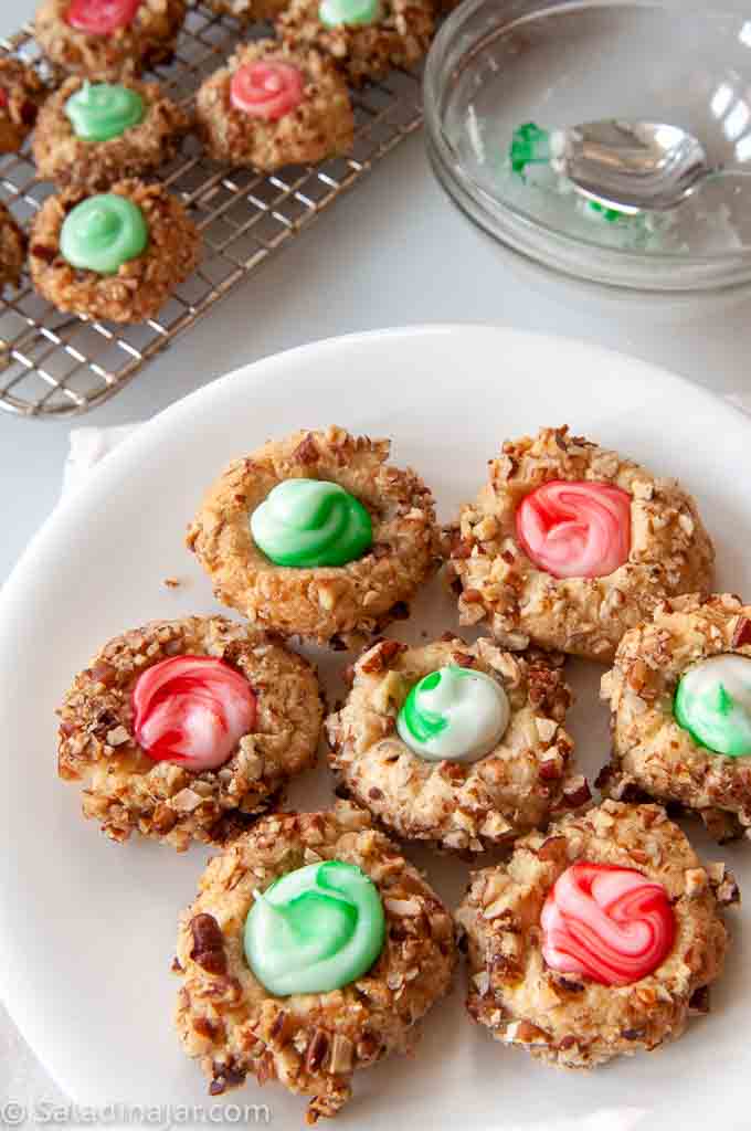 Christmas Thumbprint cookies with cooling rack and frosting bowl in the background