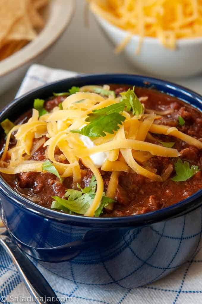 bowl of chili with chocolate and cheese on top.