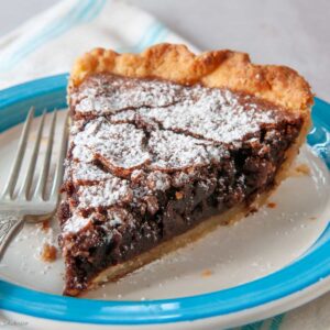 slice of chocolate fudge pie on a small plate with a fork on the side.