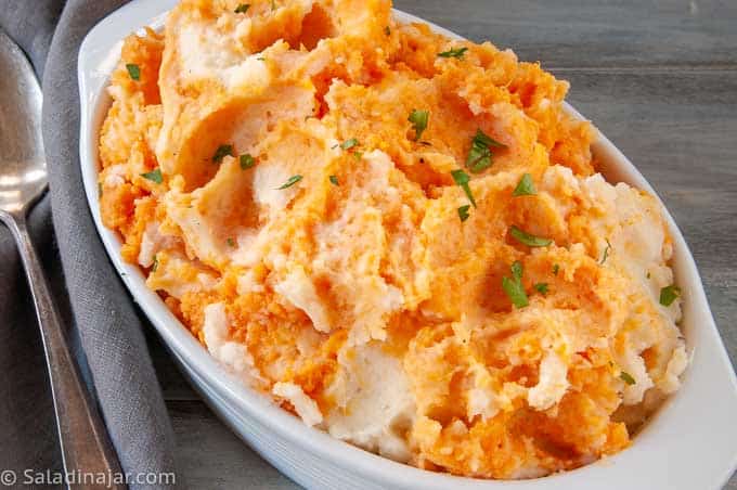 Bowl of White and Sweet Potato Mash with serving spoon
