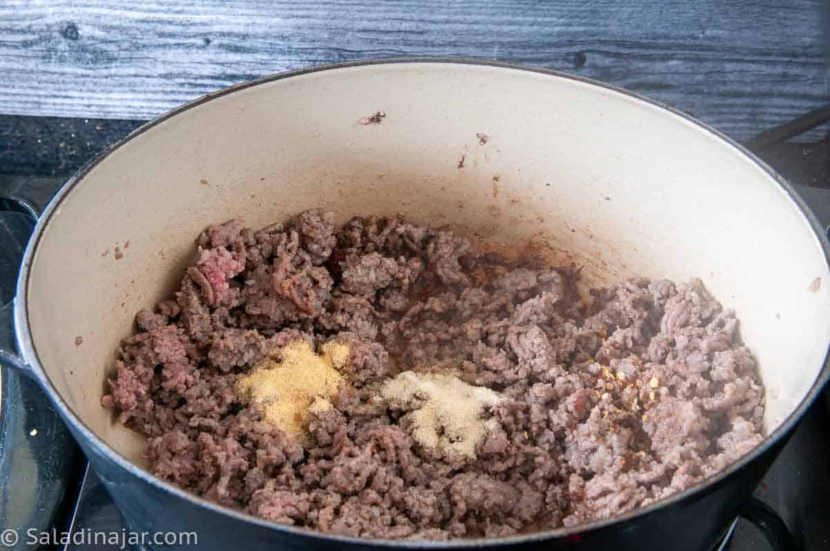 Adding onion and garlic powder to ground beef.
