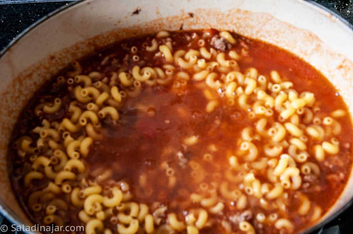 Uncooked macaroni added to pot