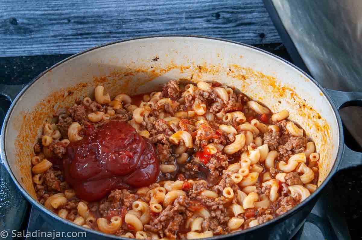 Adding additional seasoning after macaroni has cooked.