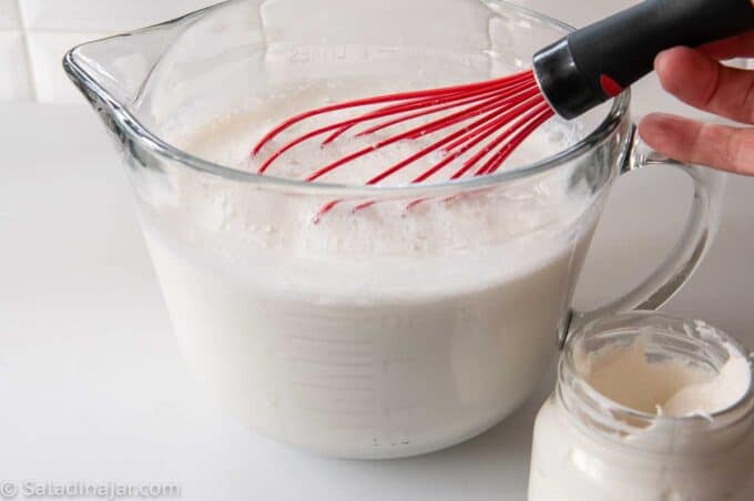 whisking warm starter into heated and cooled milk.