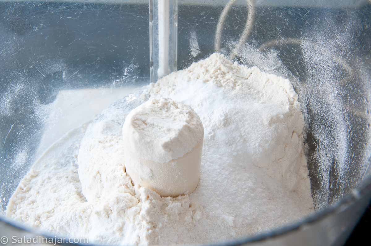 Adding dry ingredients to a food processor bowl.