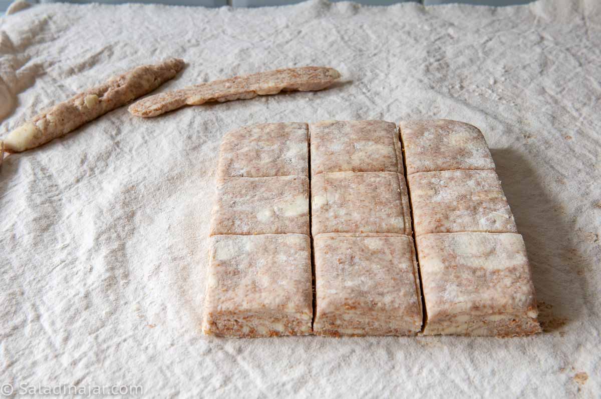 trimming the square of dough and cutting into 9 biscuits