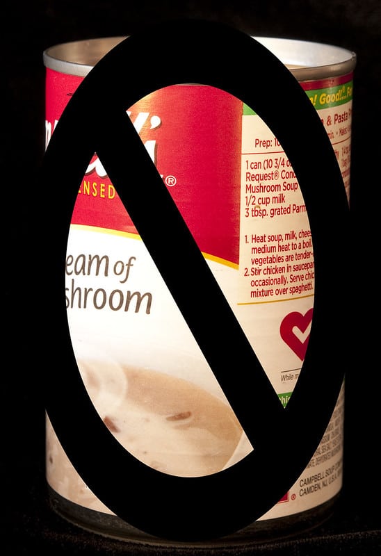 can of commercially made cream of mushroom soup with black sign over it