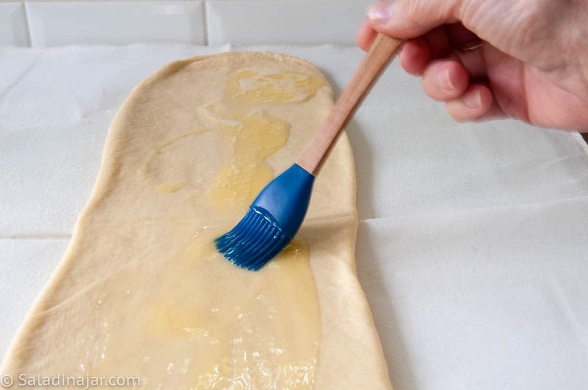brushing butter over the dough
