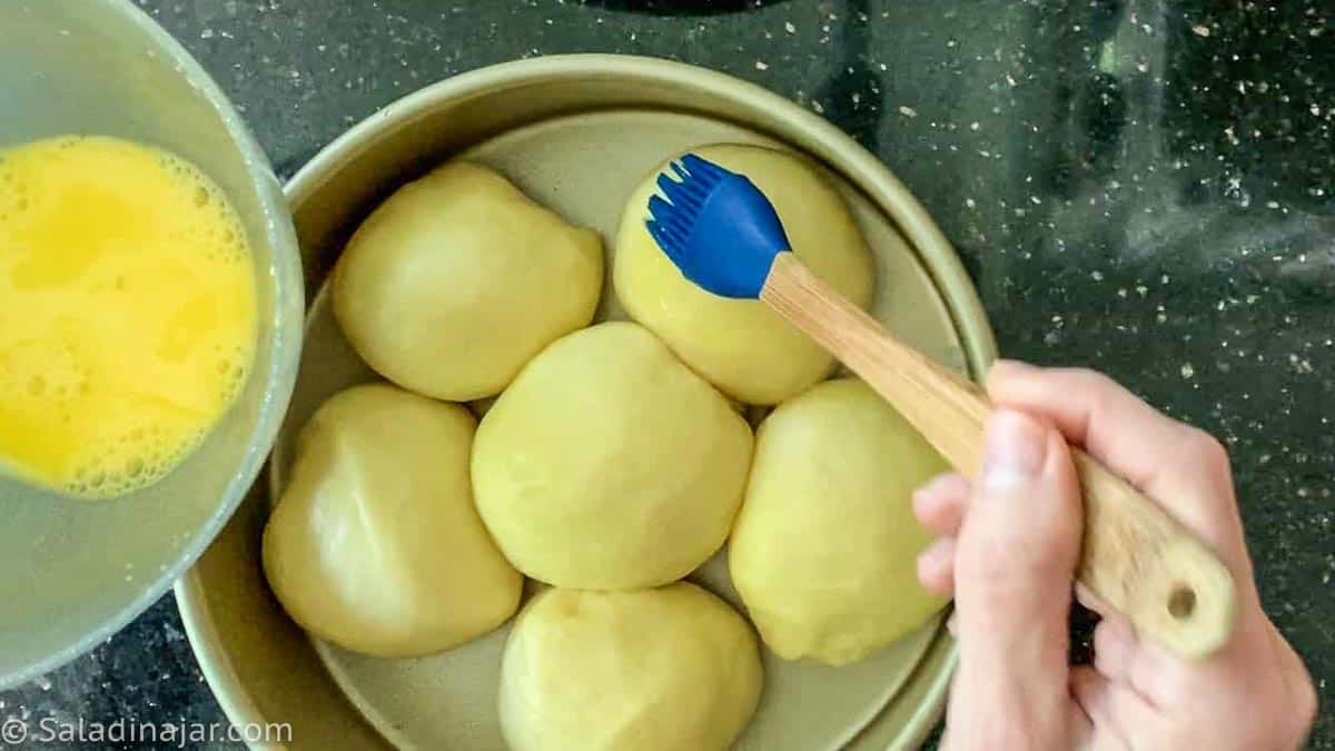 Glazing the rolls with egg yolk and milk.