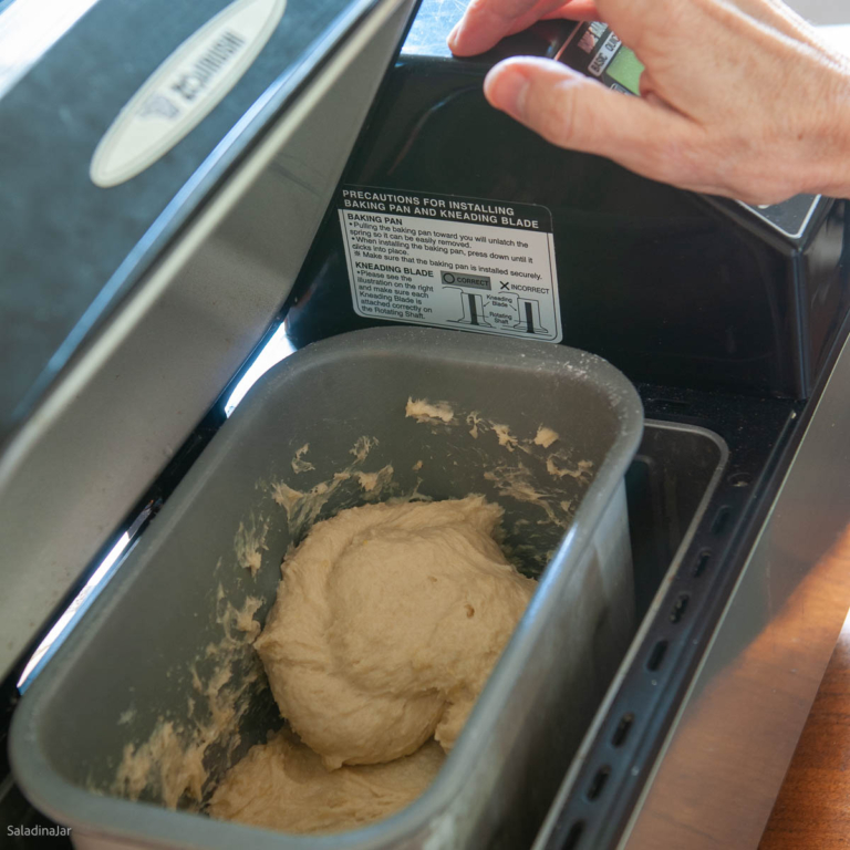 checking consistency of the dough by opening lid of bread machine