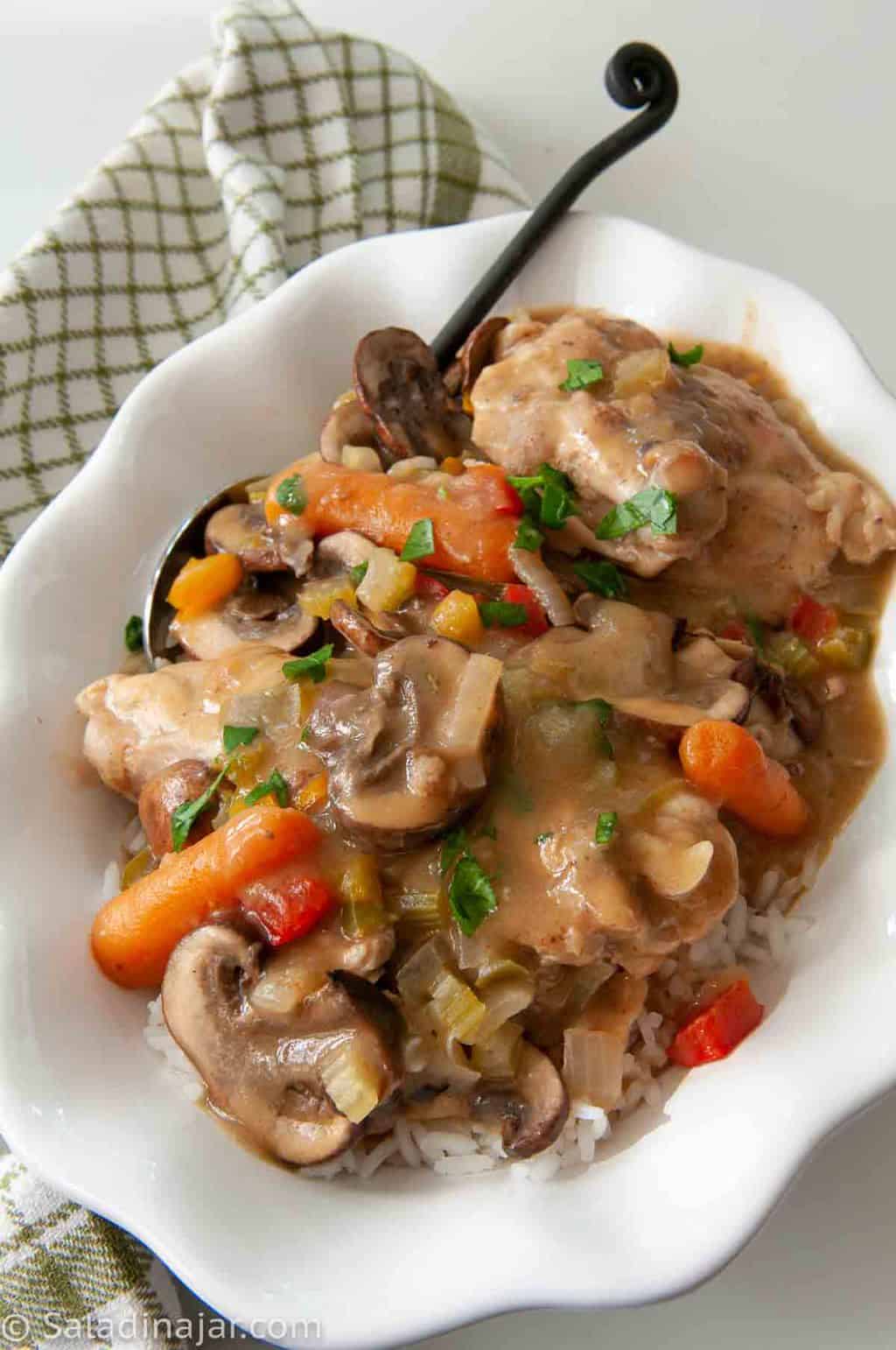 Cajun Chicken Fricassee ready to eat in a white serving dish with a serving spoon