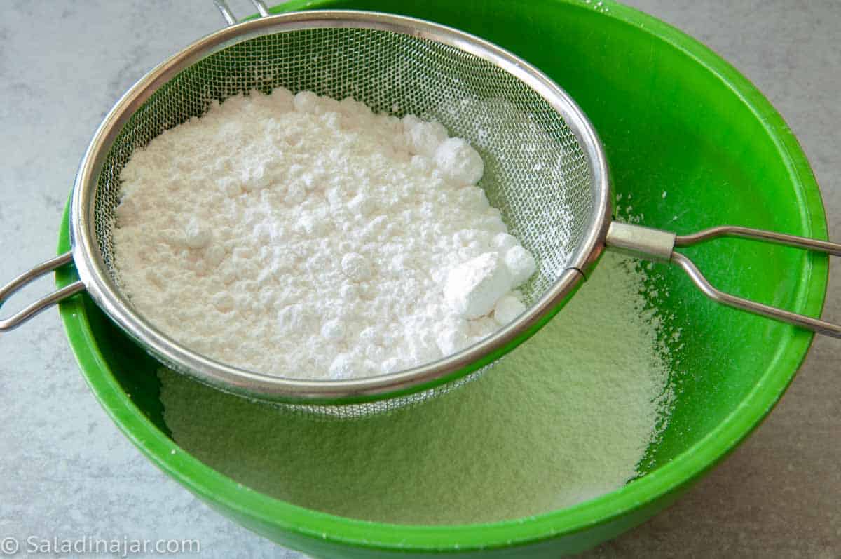 using a sieve to sift confectioner's sugar to remove lumps