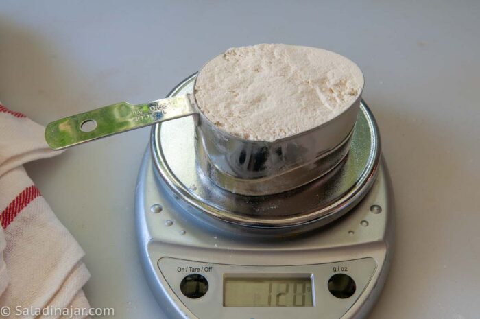 a digital scale showing that 1 cup of flour when measured correctly weighs 120 grams or 4-1/4 ounces