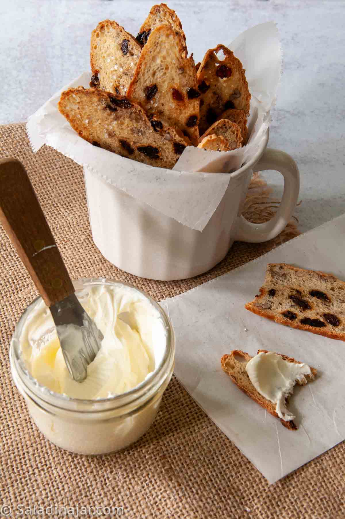 a bowl of homemade crème fraîche next to homemade melba toasts