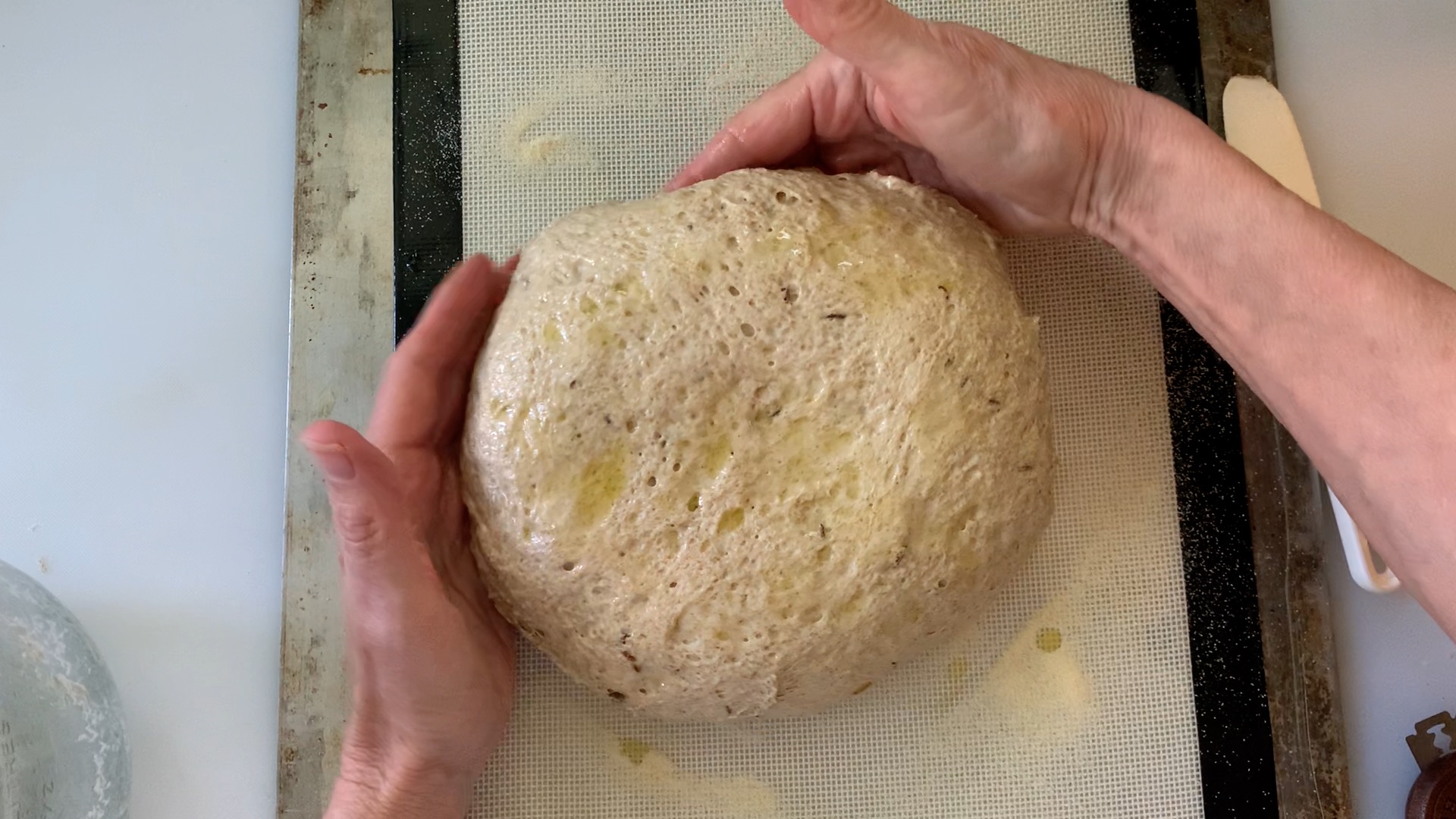 pushing dough toward the middle with hands to cause the loaf to be taller.