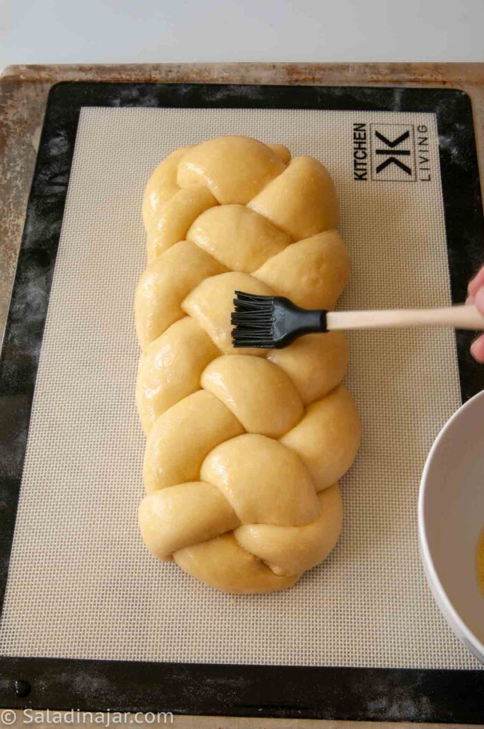 Brushing challah with egg wash before going into the oven.