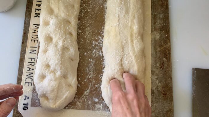 Dimpling the dough with fingertips.