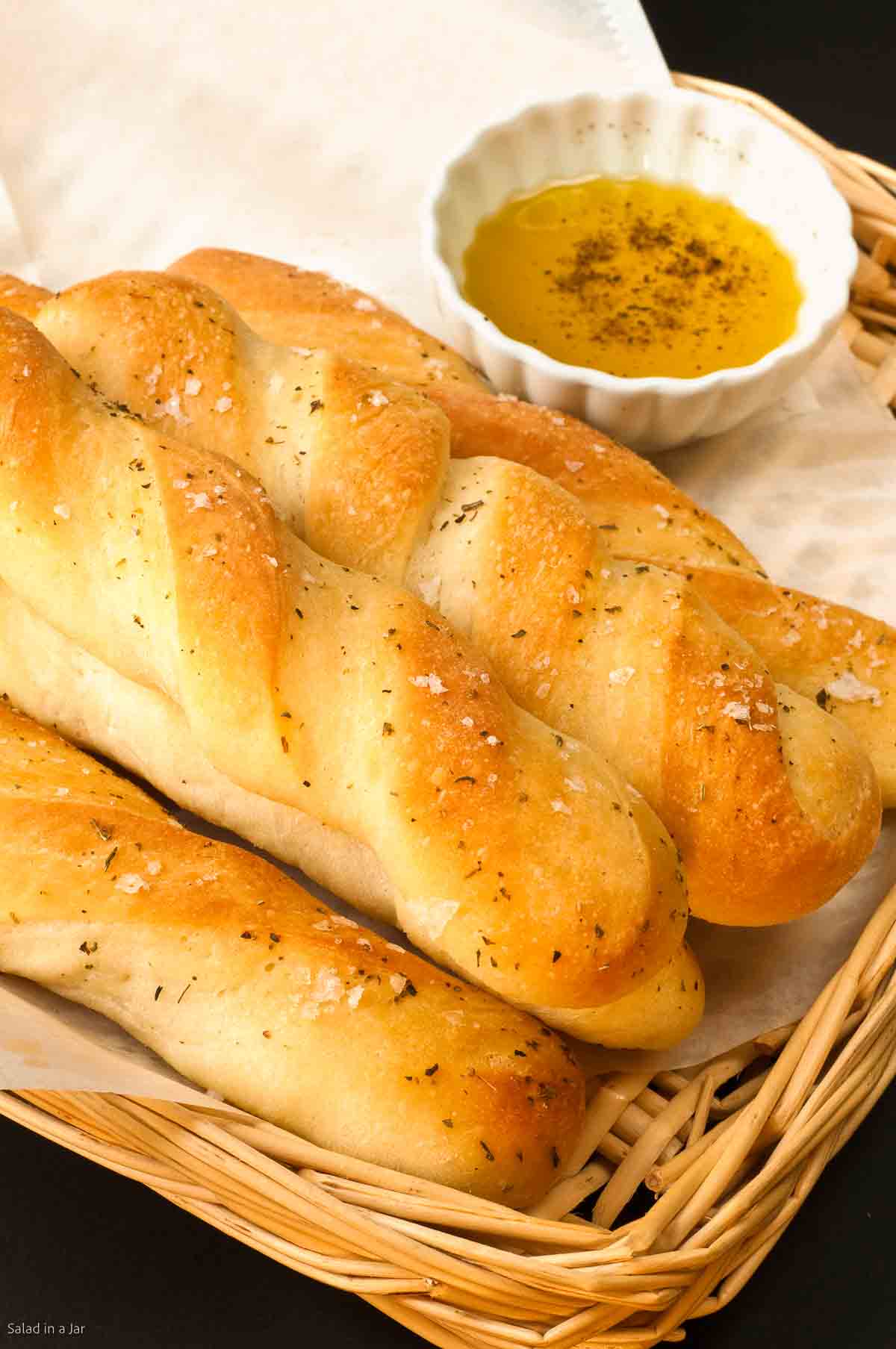 garlic bread machine breadsticks in a basket with dipping oil on the side.