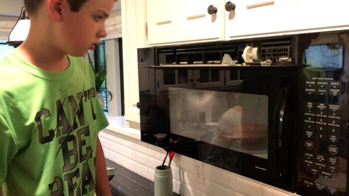 grandson popping popcorn in a microwave